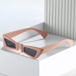 Fashionable butterfly-shaped sunglasses with pink frames and dark lenses on white pedestal