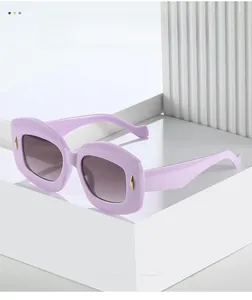 Close-up of lavender purple oval sunglasses with gold pin accents on white geometric stand