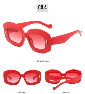 Detail view of oval sunglasses with red glossy frames and gold pin metal accents