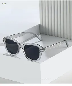 Vue détaillée des lunettes de soleil gris transparent avec verres noirs sur socle blanc