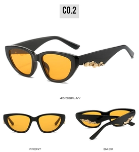 Cat eye sunglasses detail with black frame, orange lenses, and golden wavy temple decor