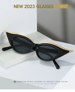 Détail de lunettes yeux de chat noires avec accents métalliques dorés sur socles blancs