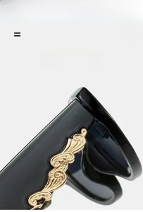 Detailed macro view of black sunglasses featuring golden floral scrollwork on the temple