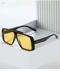Detail of oversized black frame sunglasses with yellow lenses and rivet accents