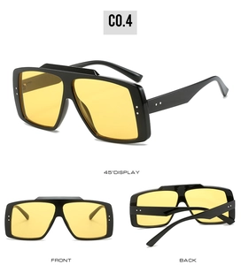 Detail view of large square sunglasses with black frame, yellow lenses, and metal rivets
