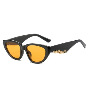 Cat eye sunglasses with black frames, orange lenses and golden wave temple details