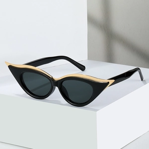 Lunettes de soleil œil de chat noires avec détails dorés sur un support blanc géométrique