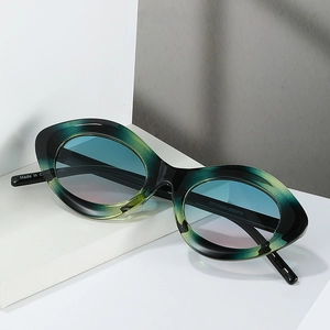 Lunettes de soleil œil de chat vertes avec verres dégradés bleus sur socle blanc