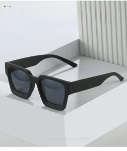 Detail of matte black square sunglasses on a white geometric stand with textured backdrop