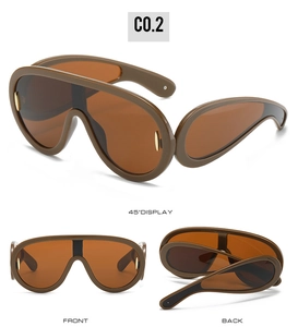 Detail view of oversized futuristic visor sunglasses with amber frame and gold metal accents