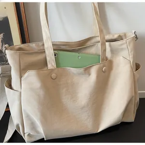 Detail of beige Oxford cloth tote bag showing functional front pocket with tablet storage