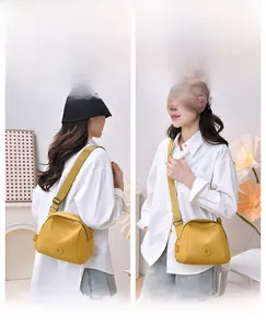 Detail of ginger yellow nylon crossbody bag showing the adjustable strap and round logo