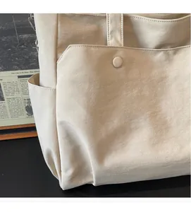 Close-up of beige Oxford fabric tote bag with functional pockets and soft texture detail