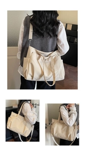Detail view of large beige oxford tote bag showing side pockets and adjustable strap