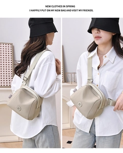 Detail view of the beige oxford crossbody bag showing zippers and wide fabric strap