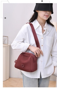 Close-up of wine red oxford cloth shell bag with multi-layer zippers and wide strap