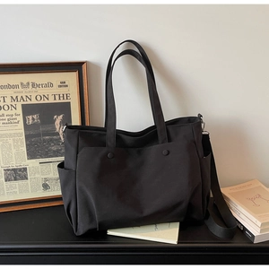 Detail view of durable black oxford tote bag with multiple pockets and adjustable shoulder strap