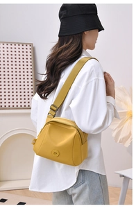 Detail of a bright yellow nylon shell crossbody bag with adjustable wide strap on model