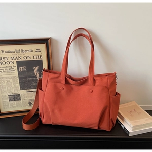 Orange oxford tote bag with sturdy handles and wide shoulder strap in lifestyle setting