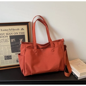 Detail view of large orange oxford tote bag with multiple pockets and shoulder strap