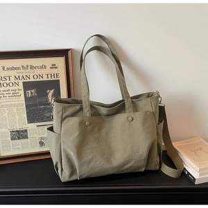 Detail view of olive green canvas tote bag with adjustable strap and side pockets