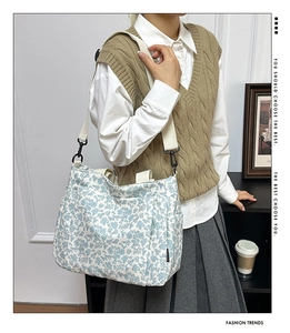 Detail of floral canvas tote bag featuring blue flower patterns and wide beige shoulder strap