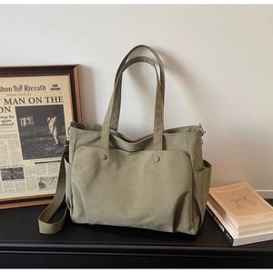 Detailed view of an olive green canvas tote bag with multiple pockets and shoulder strap
