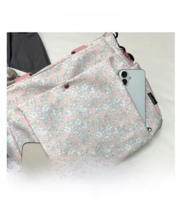 Detailed view of the pink floral tote bag showing front pockets holding two smartphones