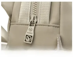 Detail of smooth khaki Oxford cloth with branded metal zipper pull and leaf logo