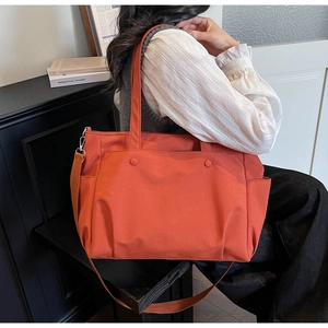 Detail of orange thickened oxford tote bag featuring reinforced handles and side pocket