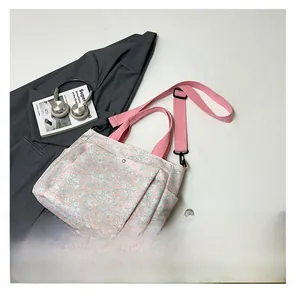 Detail view of floral tote bag with pink straps and adjustable shoulder belt