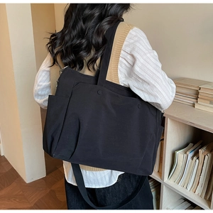 Detail view of large black Oxford tote bag with multiple pockets and adjustable shoulder strap