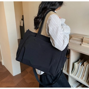Detail of black oxford tote with multi-pockets, showing size scale on model in home setting