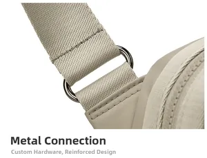 Detail view of reinforced stitching and dark metallic D-ring on beige oxford bag strap