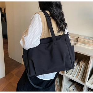 Detailed back view of a person wearing a black Oxford fabric large capacity tote bag