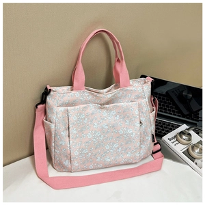 Detail of light pink floral canvas tote bag with multiple pockets on a white desk