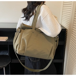 Olive green Oxford tote bag with adjustable strap and side pocket on female model