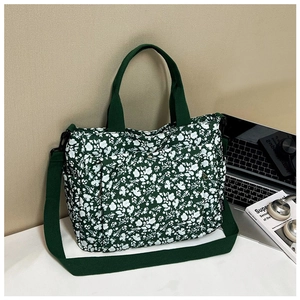Detail of green floral canvas tote bag featuring side pocket and adjustable strap