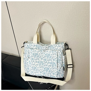Detail of blue floral canvas tote bag with adjustable strap and functional side pocket