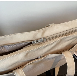 Close-up of beige Oxford tote bag featuring silver zipper and herringbone fabric lining