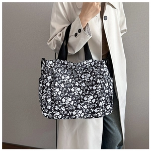Detail view of large floral tote bag with side pockets and black shoulder straps