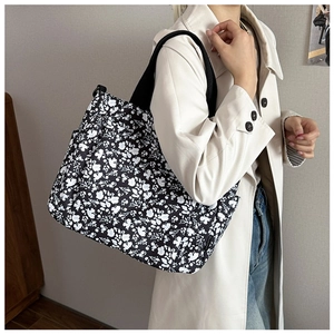 Floral canvas tote bag shown on shoulder of a model for size and style reference
