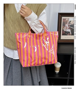 Détail du sac fourre-tout en PVC brillant à rayures verticales avec lettrage TOTE BAG