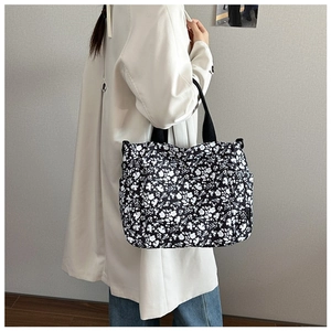 Close-up of floral tote bag with black canvas texture and side pocket detail
