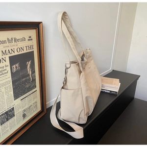 Detail of off-white thick oxford tote with adjustable strap and side storage pockets