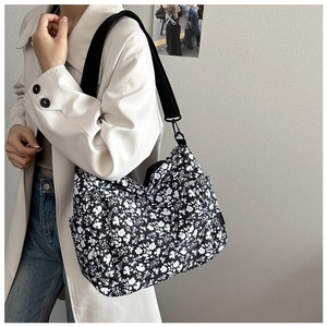 Detail of floral canvas tote bag with wide nylon strap and side pocket on model
