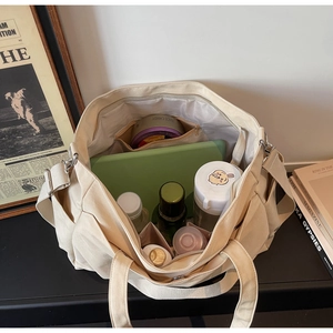 Detail view of large beige canvas tote bag showing spacious interior with multi-pocket design