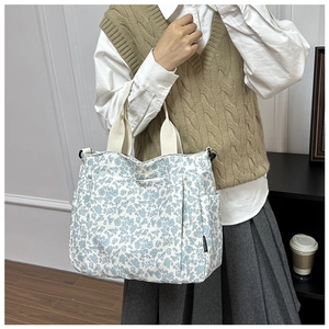 Detail of floral canvas tote bag with reinforced handles and side pocket on a model