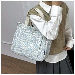 Close-up of floral canvas tote bag featuring side pocket and cream woven handles