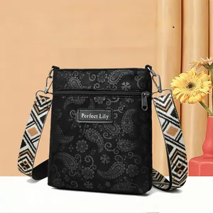 Detail of black paisley crossbody bag with geometric woven strap and leather logo patch
